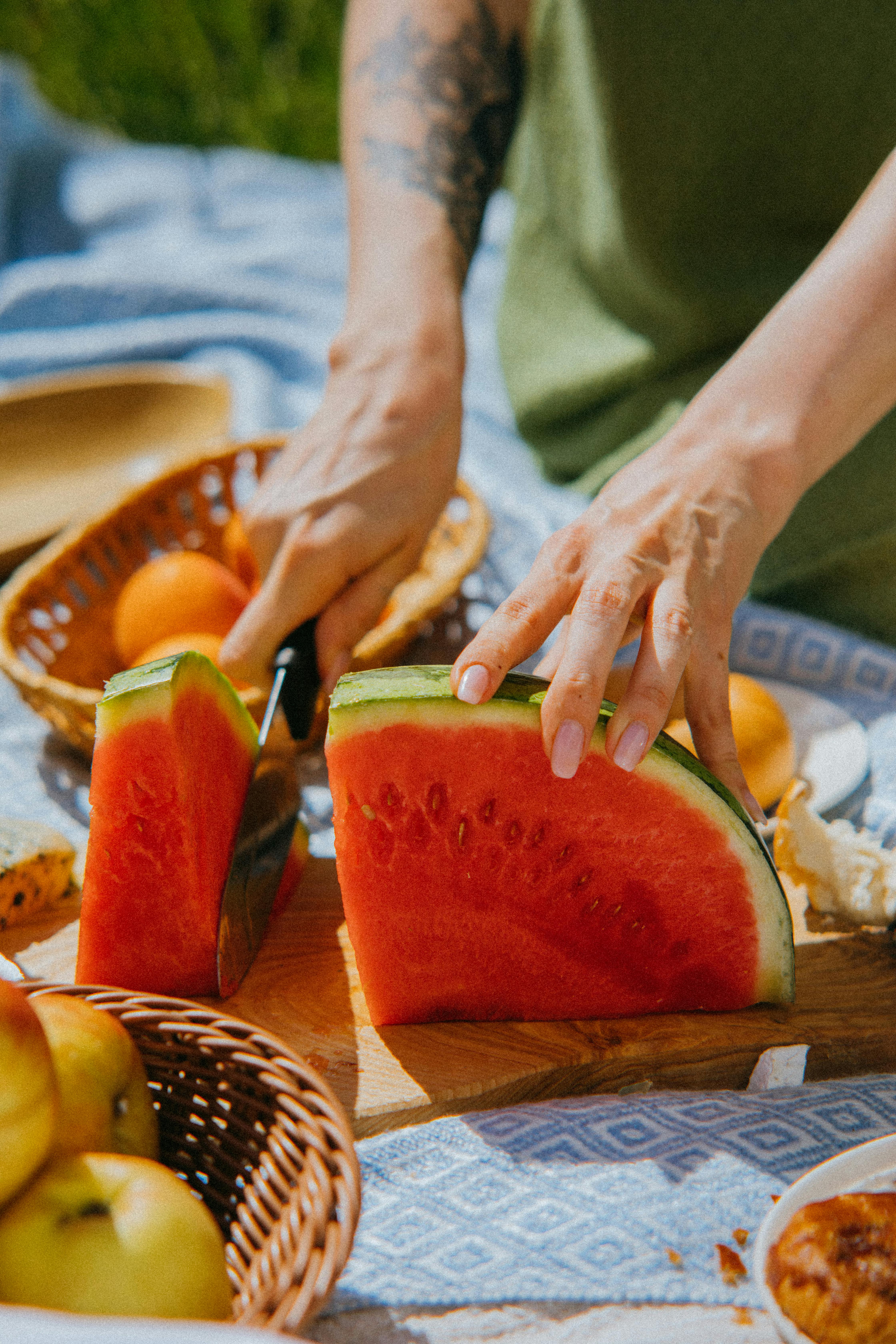 Slicing a fresh Charleston Gray watermelon on a wooden board a person slicing Charleston Gray Watermelon on wooden chopping board